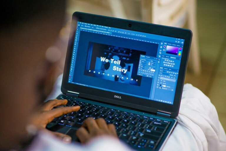 A person uses a laptop to edit images - we look over his shoulder at the screen as he works